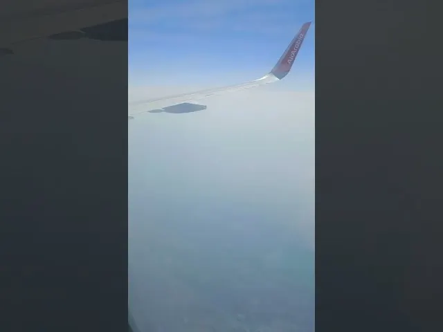 Airplane wing view from window during flight in clear sky