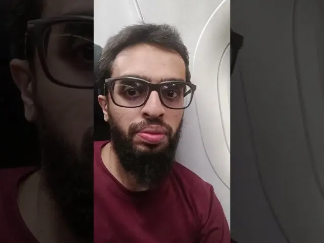 Man wearing glasses and maroon shirt on airplane