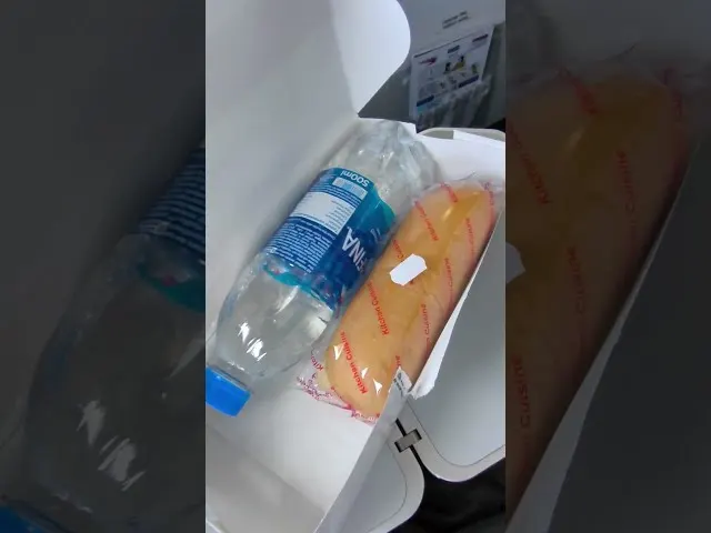 Water bottle and snack food on airplane tray table during flight