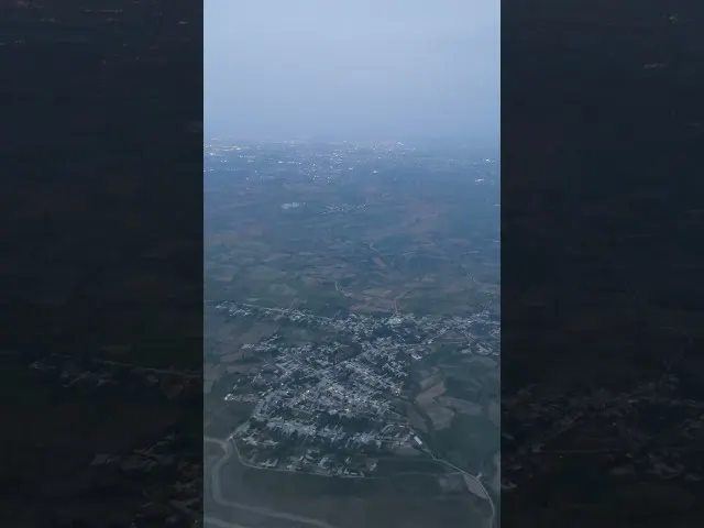 Aerial view of town settlement surrounded by agricultural fields and haze