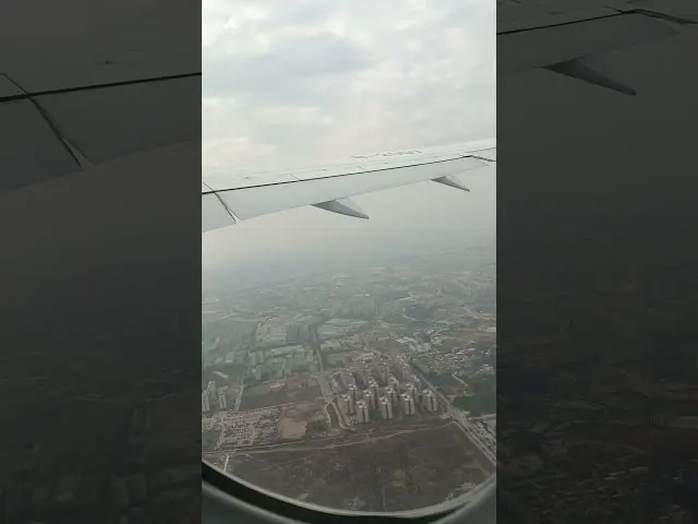 Aircraft wing view over sprawling cityscape during descent approach