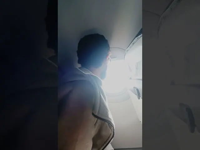 Passenger looking out airplane window during flight bright daylight