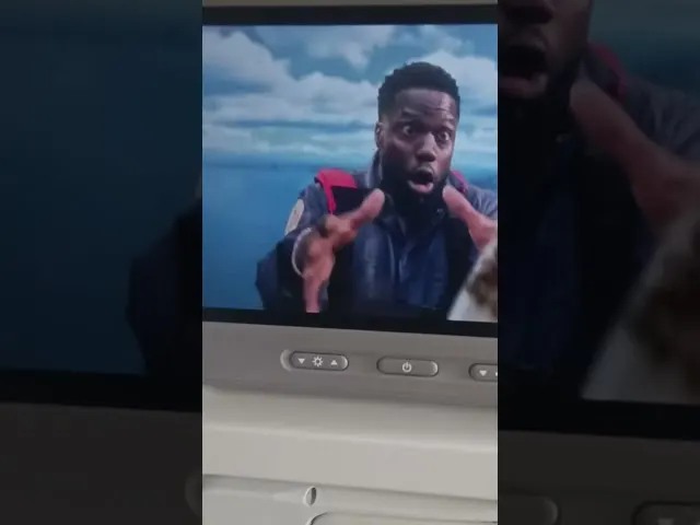 Man gesturing while speaking on airplane seat back screen display