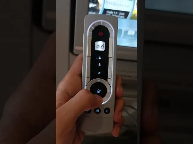 Hand holding airplane seat remote control with display screen