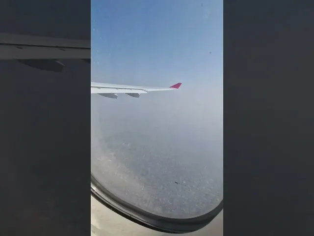 Aircraft wing and fuselage view from passenger window during flight