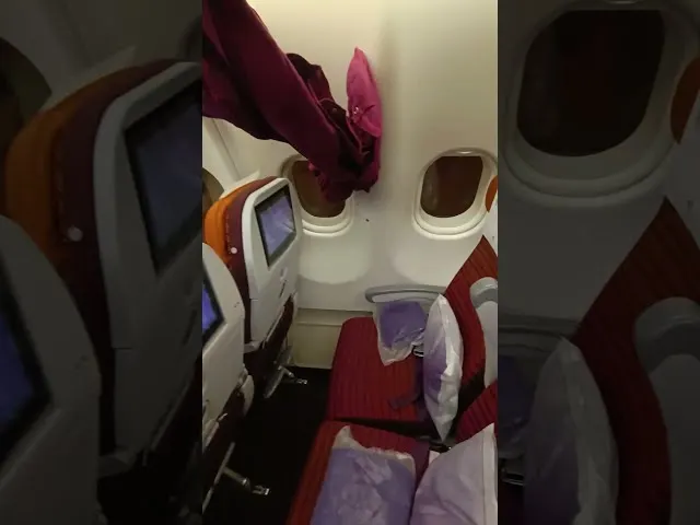 Airplane cabin interior with red seats and individual entertainment screens