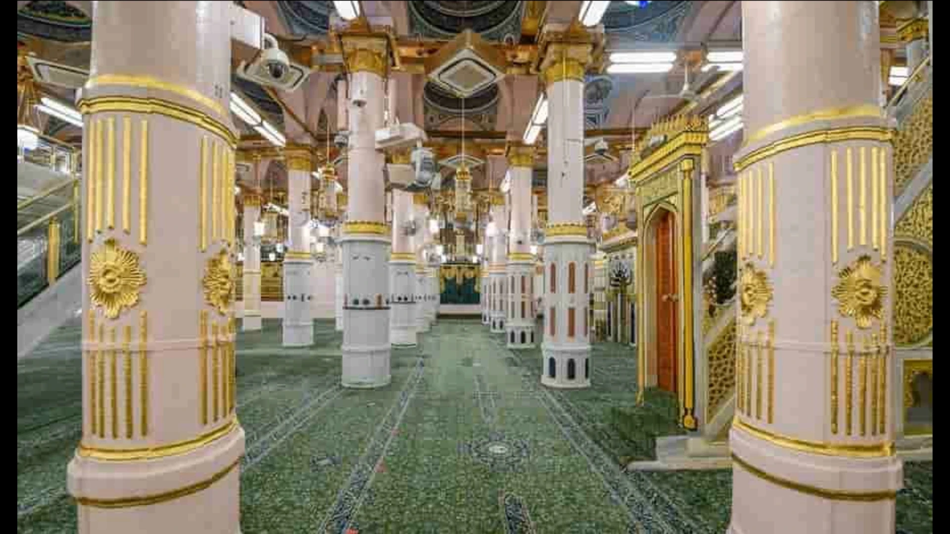 Interior of Masjid Nabawi, rows of white and gold pillars stretching toward the Rawdah, green carpet underfoot