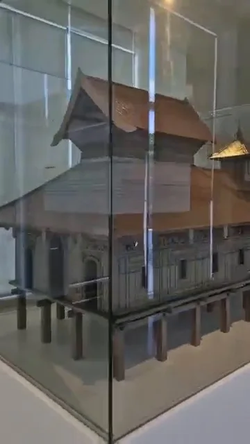Traditional wooden Southeast Asian mosque miniature model inside glass display case at Islamic Arts Museum Malaysia