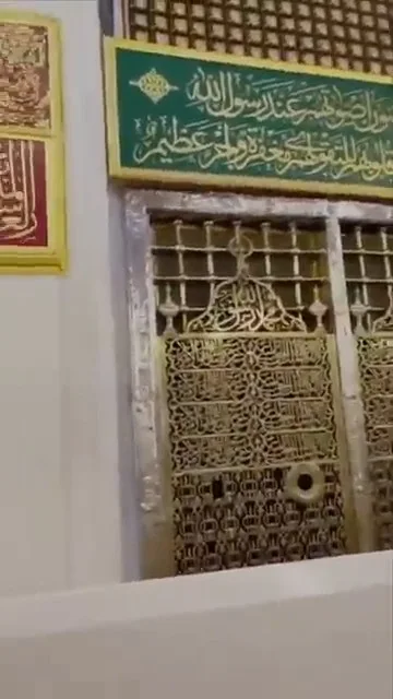 Golden grills of the Prophet's chamber with green calligraphy banner above inside Masjid Nabawi